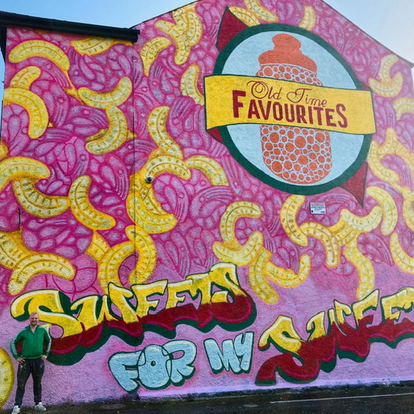 Our Mural with our Logo and very colourful yellow Sweetie Bananas and bright pink Foam Shrimps. With the artist Pigment Space in photo. 